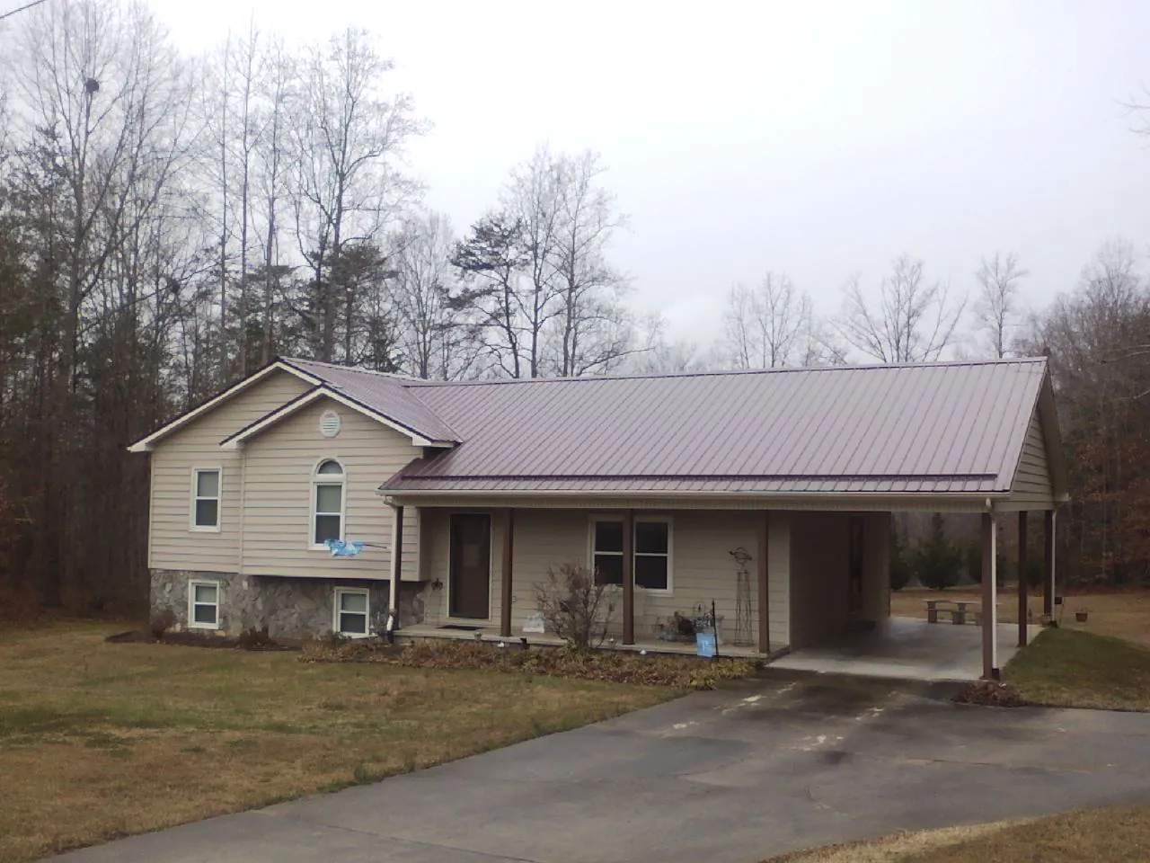 Burgundy metal roof on a tan split level home with an attached carport in Albion