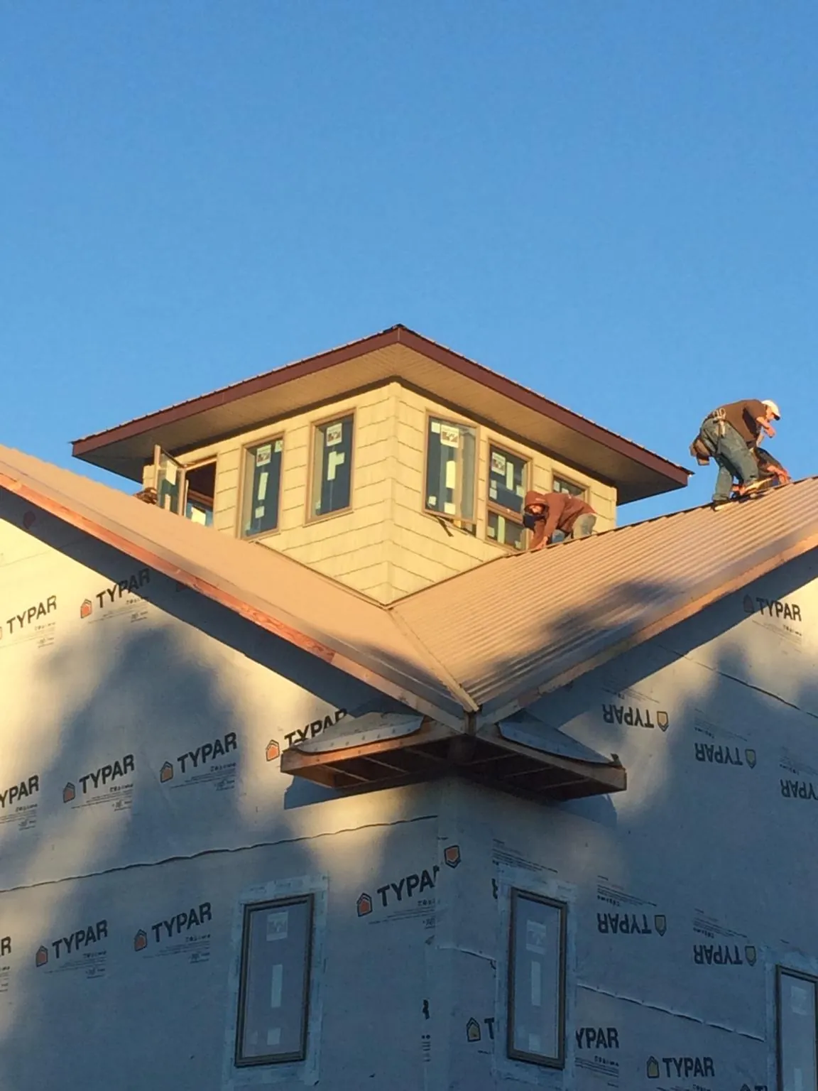 Roofers working around a rooftop cupola on a new metal roof at sunset — Roof Waterproofing in Albion by Roofing Brothers